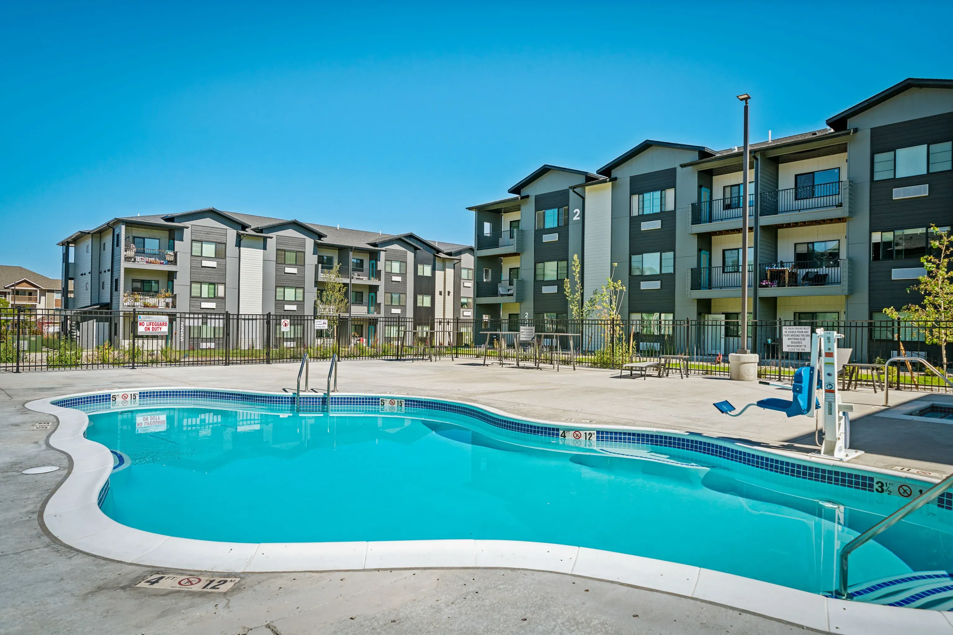 Outdoor pool at an apartment community with multi-story buildings in the background.