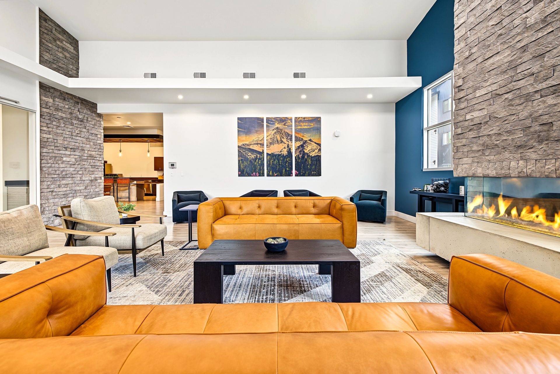 Modern living room with orange sofas, fireplace, blue accent wall, and large windows