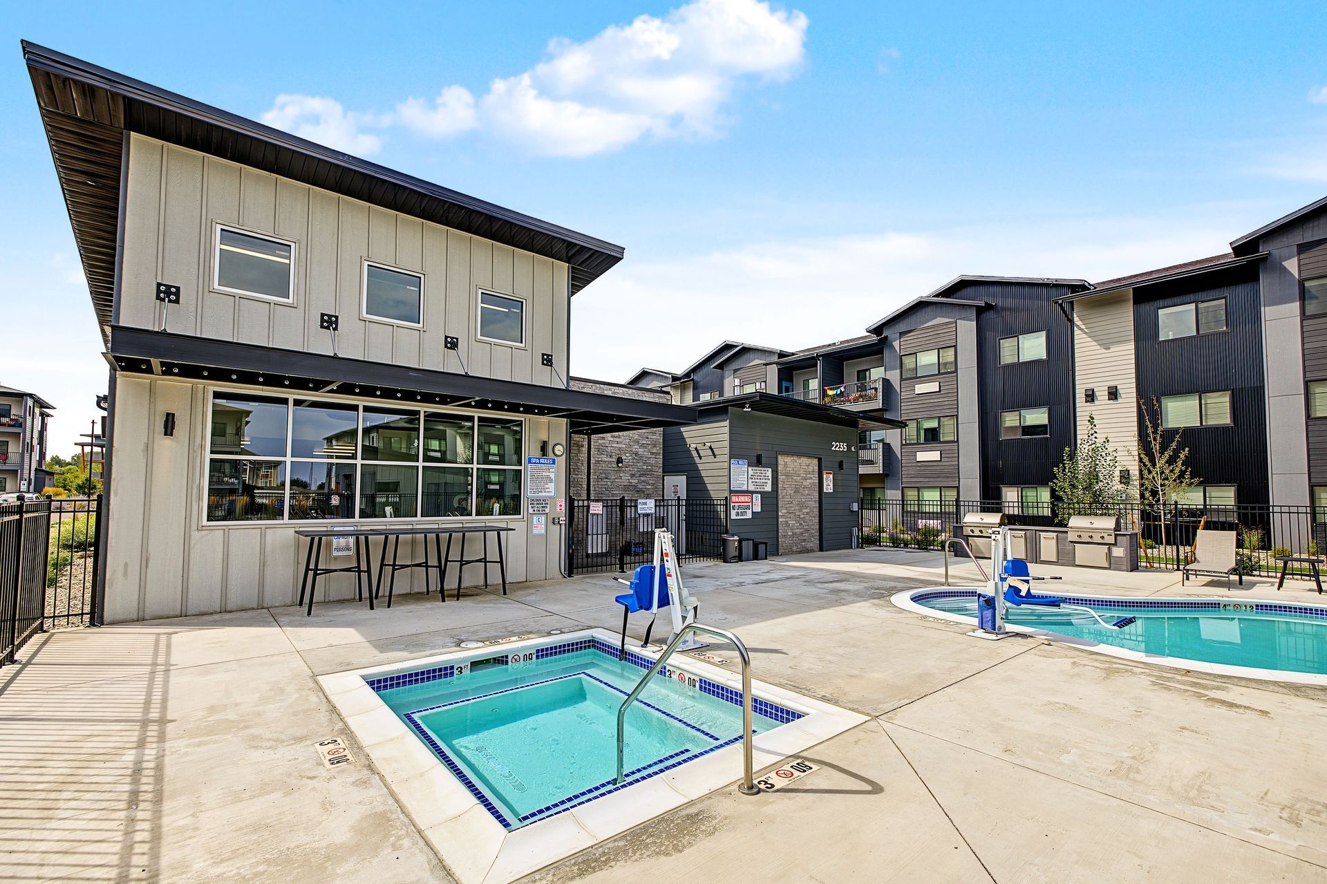 Outdoor apartment courtyard with a blue swimming pool and lounge chairs on a sunny day