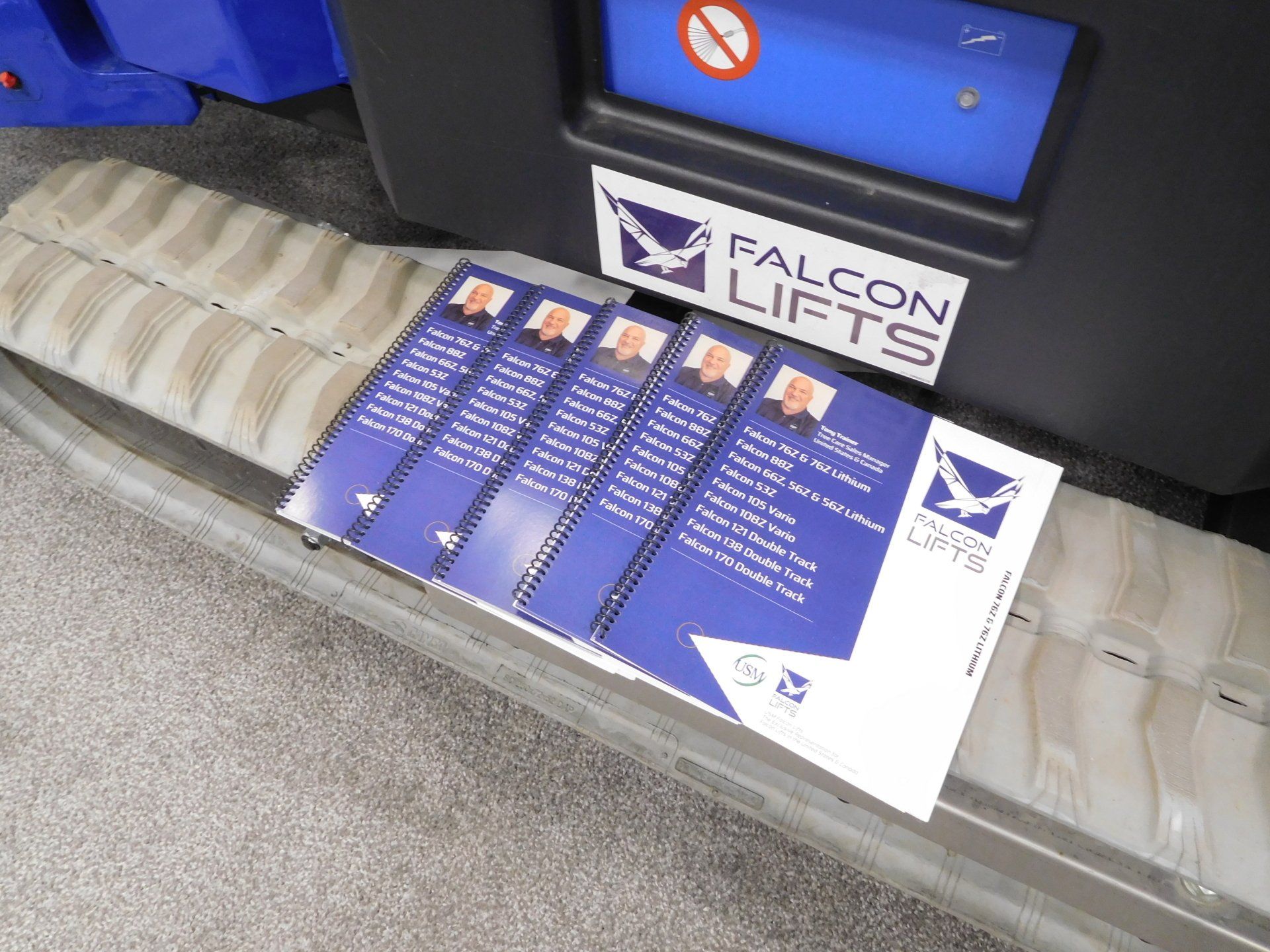 A stack of falcon lifts brochures on a conveyor belt