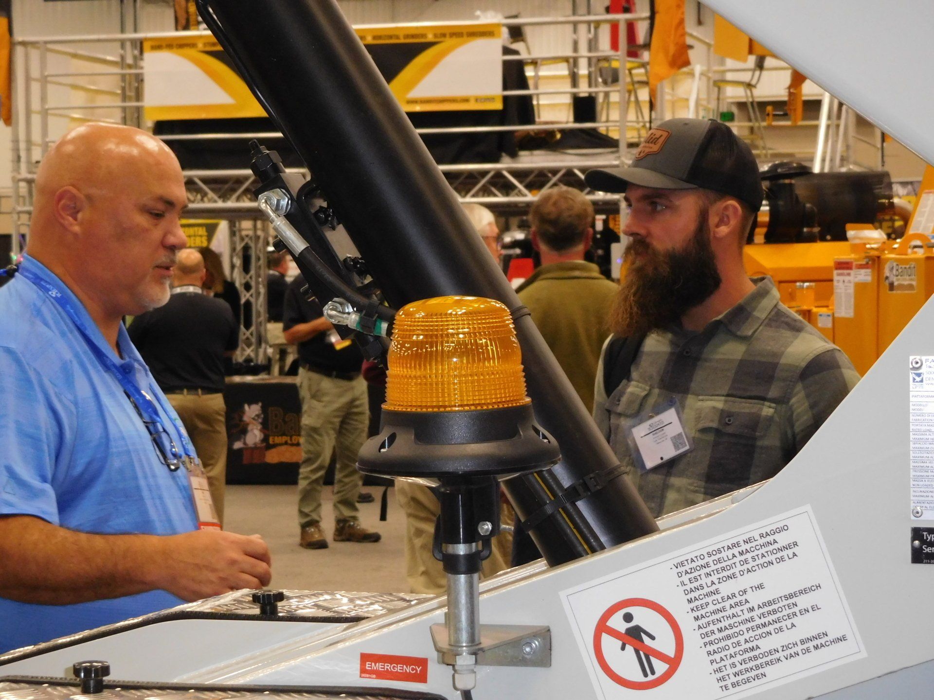 A man with a beard is talking to another man in a factory
