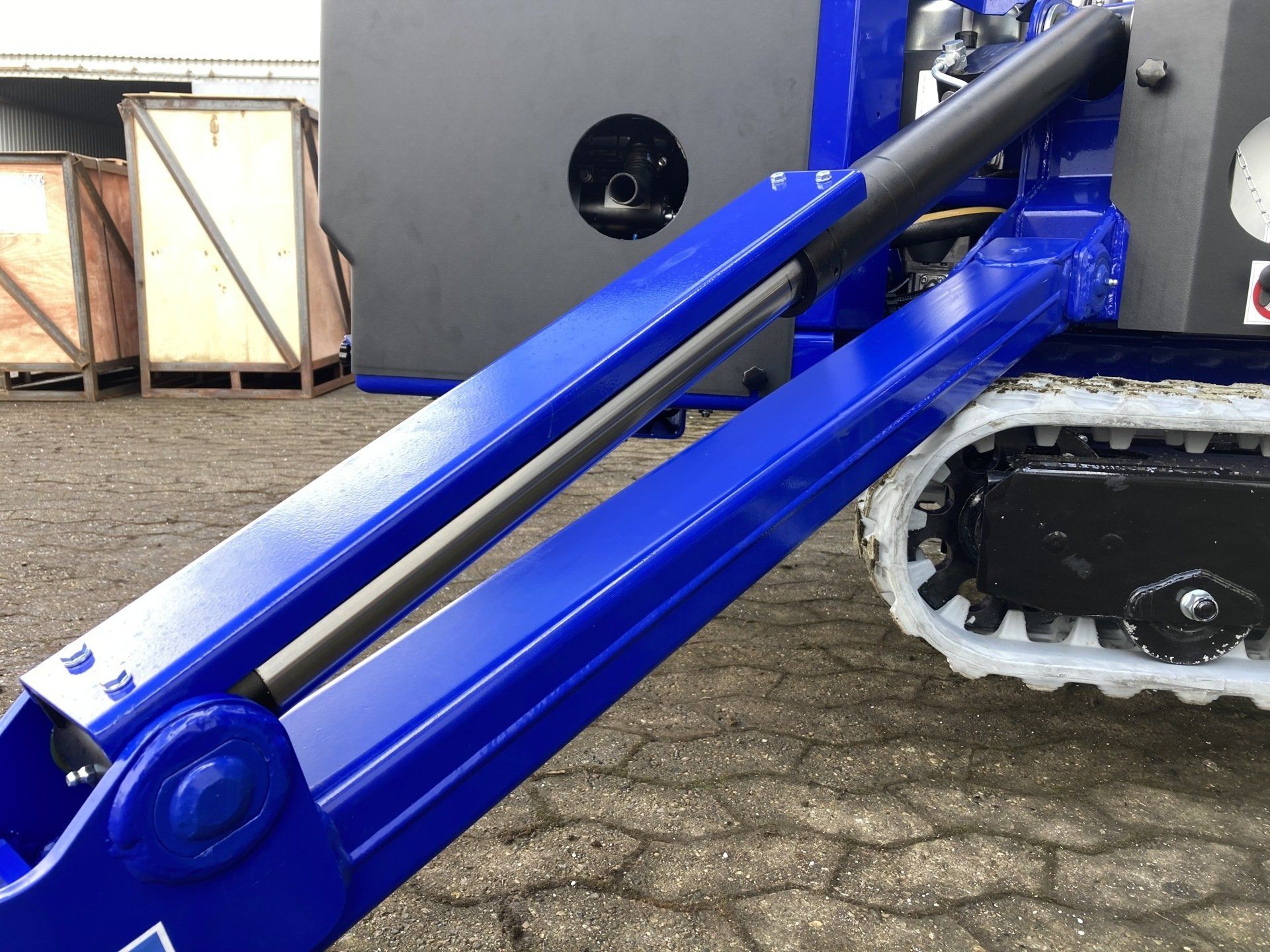 A blue and black machine is parked on a brick road.