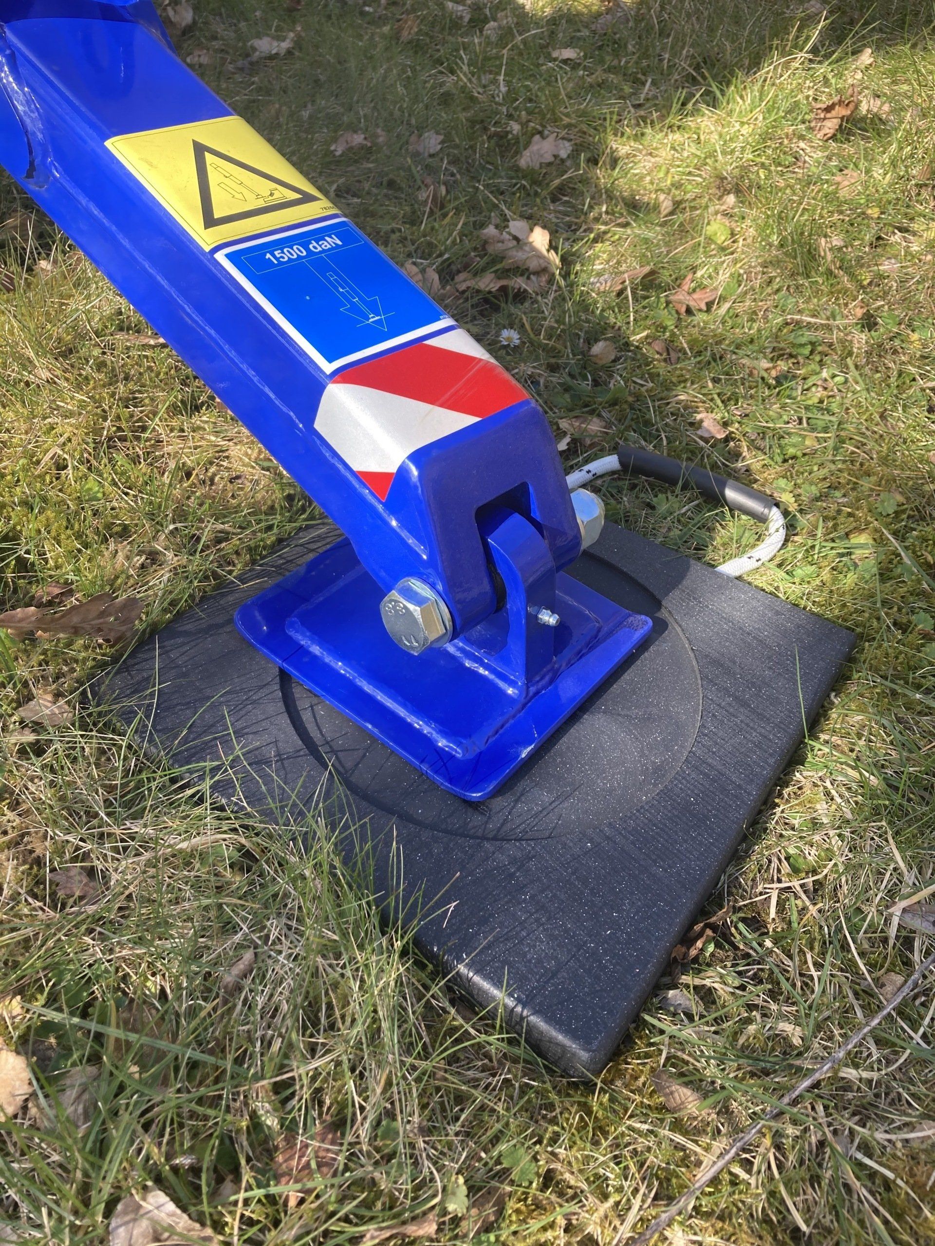 A blue crane is sitting on a black mat in the grass