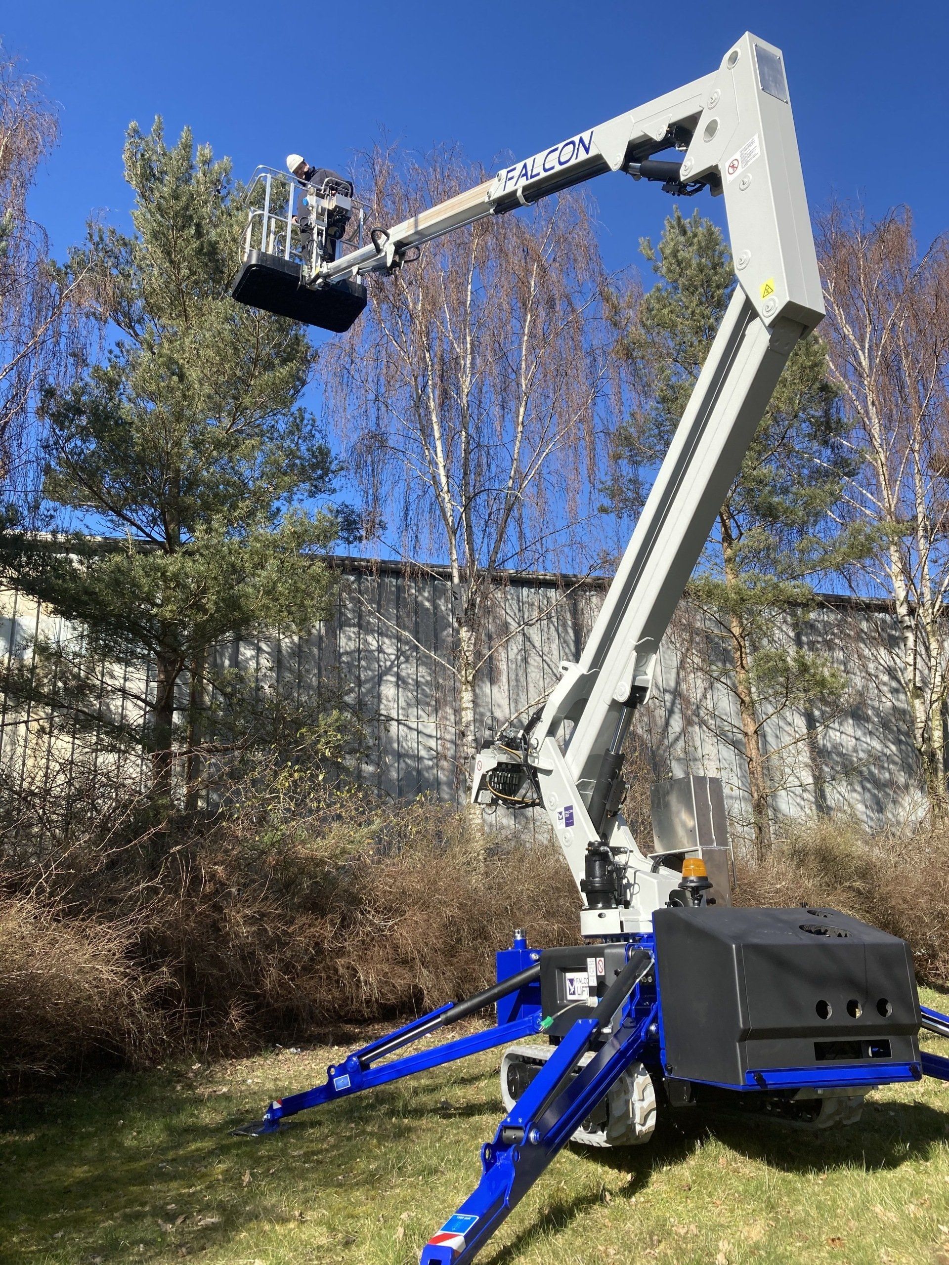 A crane is sitting in the grass in front of a building.