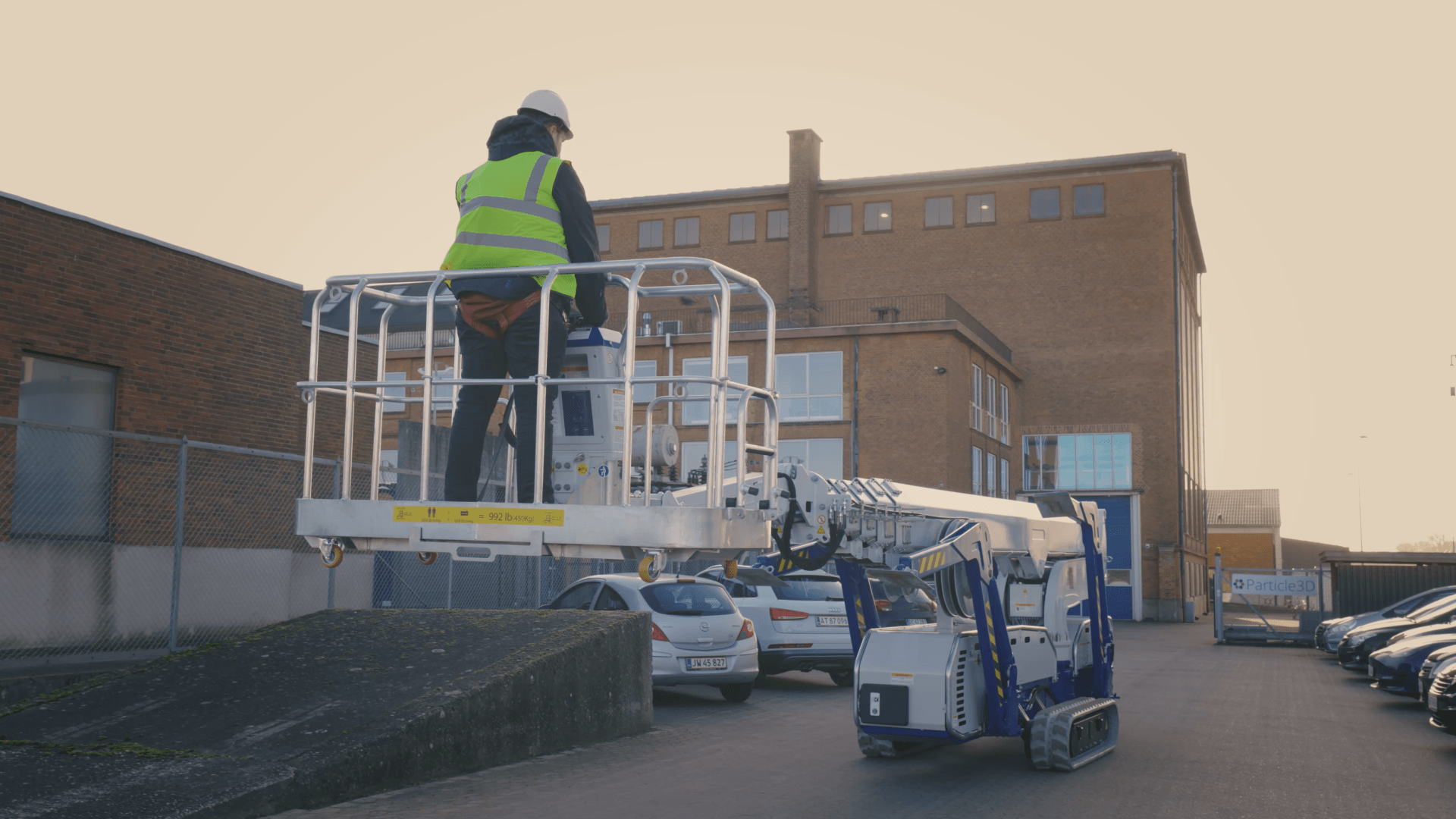 A man is standing in a bucket on a lift in front of a building.