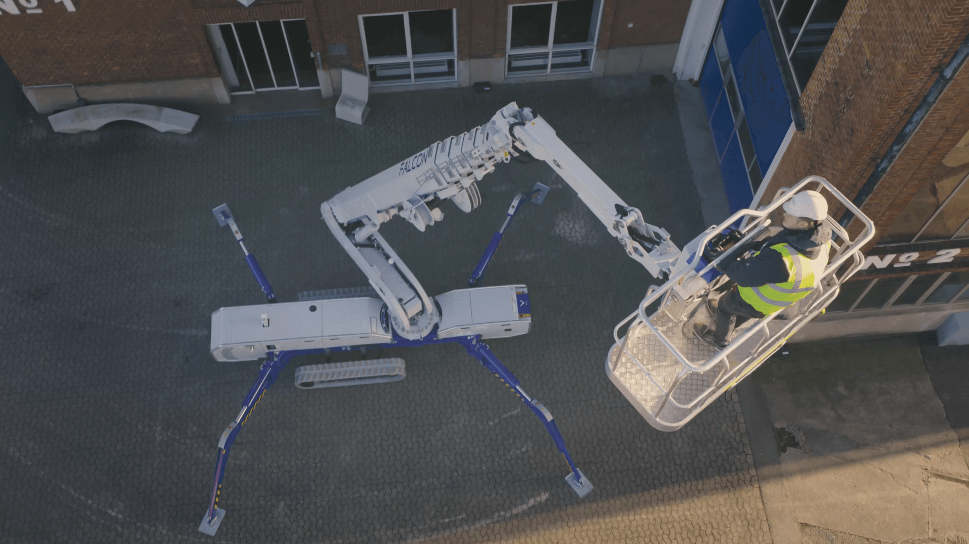 An aerial view of a man in a bucket on a crane.