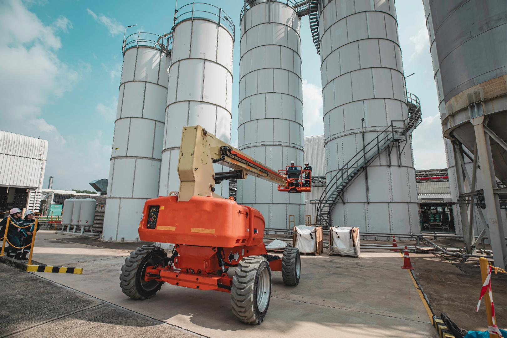A red JLG 800AJ articulating boom lift extended to 80 ft positioned on a gravel job site with construction in the background