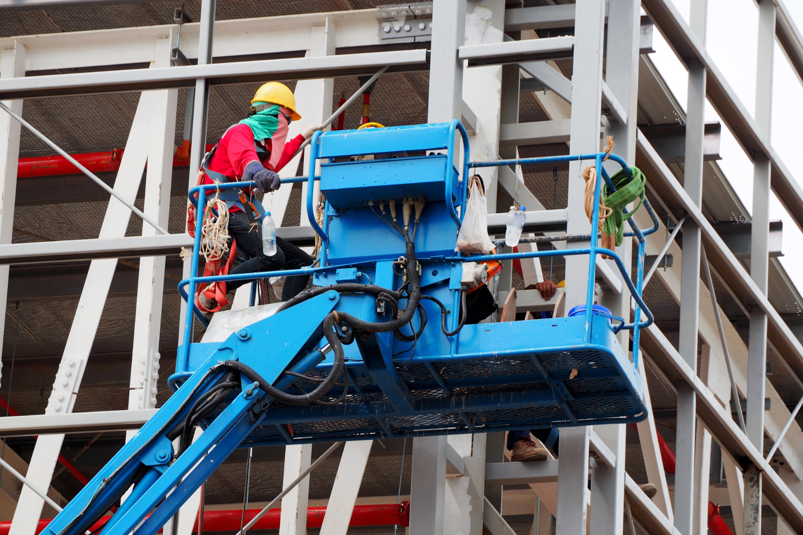 Construction worker at construction site using lifting boom machinery