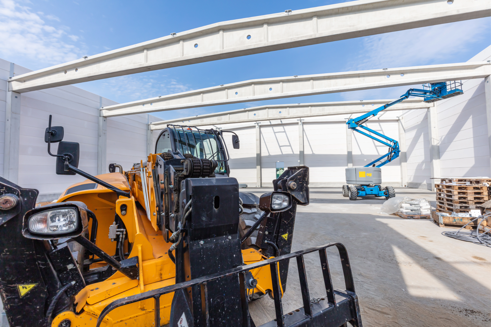 Dieci 11.58-C telehandler and Genie Z80/60 boom lift at warehouse construction site with steel frame and concrete floor