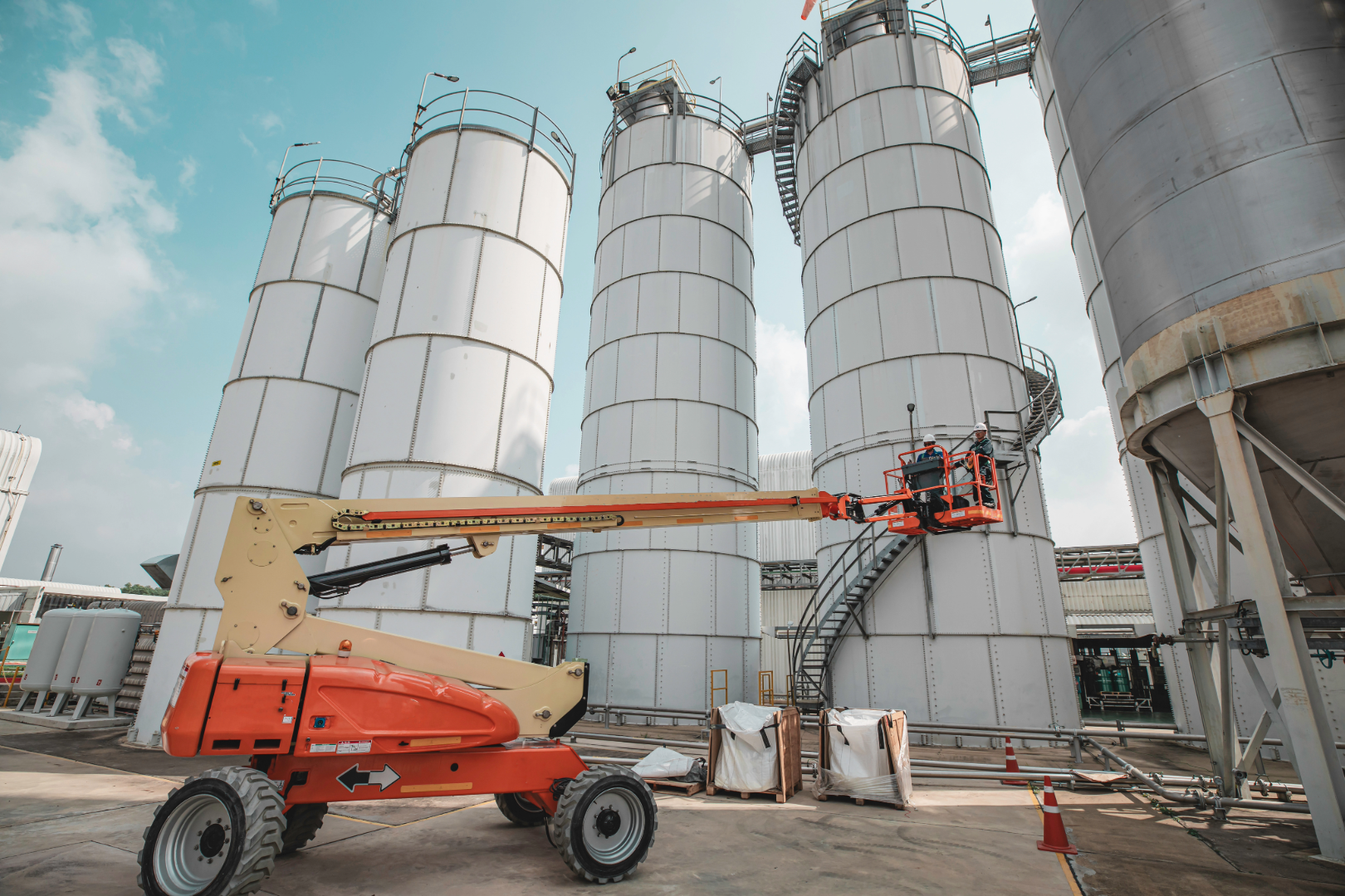 Construction workers working on large scale telescopic boom lift platforms for massive warehouse and factory building