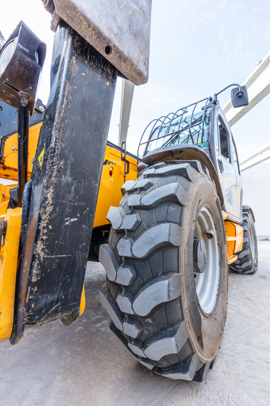 Industrial warehouse build with yellow Dieci 11.58-C rotating telehandler on site under steel beams and clear blue sky