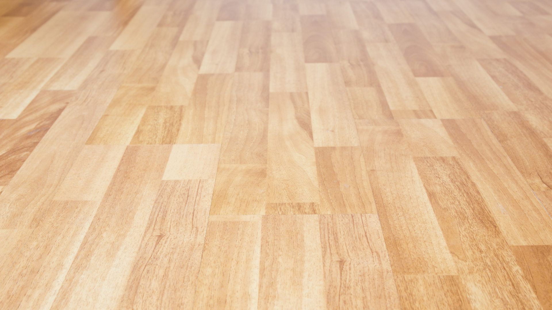 A close-up, angled view of a light-colored wood laminate floor with a natural grain pattern.
