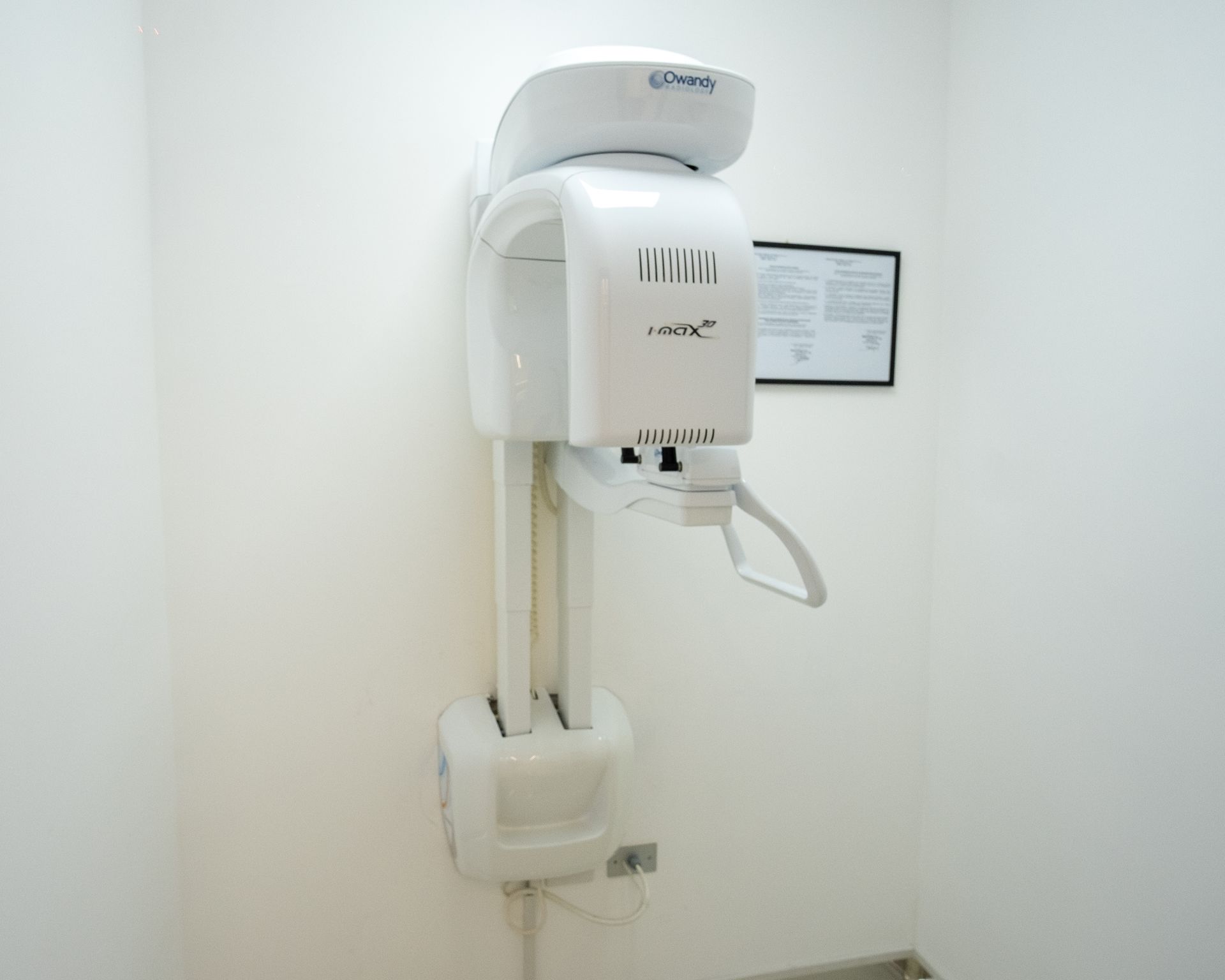Apparecchio radiografico dentale a parete in una sala visite pulita e bianca.