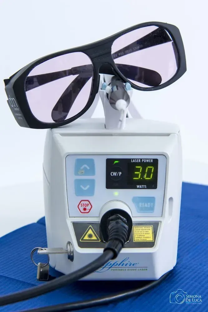 Occhiali neri su una macchina laser con display digitale e tubo blu