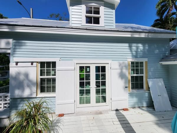 A light blue house with white shutters on the windows