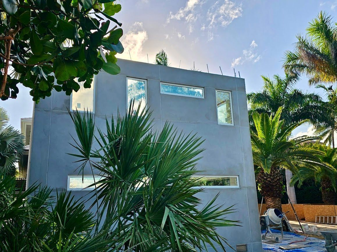 A large concrete building with a lot of windows is surrounded by palm trees.