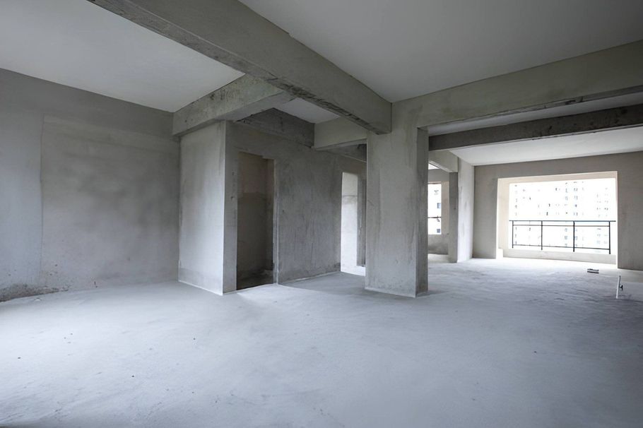 Empty unfinished concrete apartment interior with large windows and exposed beams