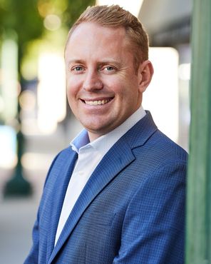 A man in a blue suit and white shirt is smiling for the camera.