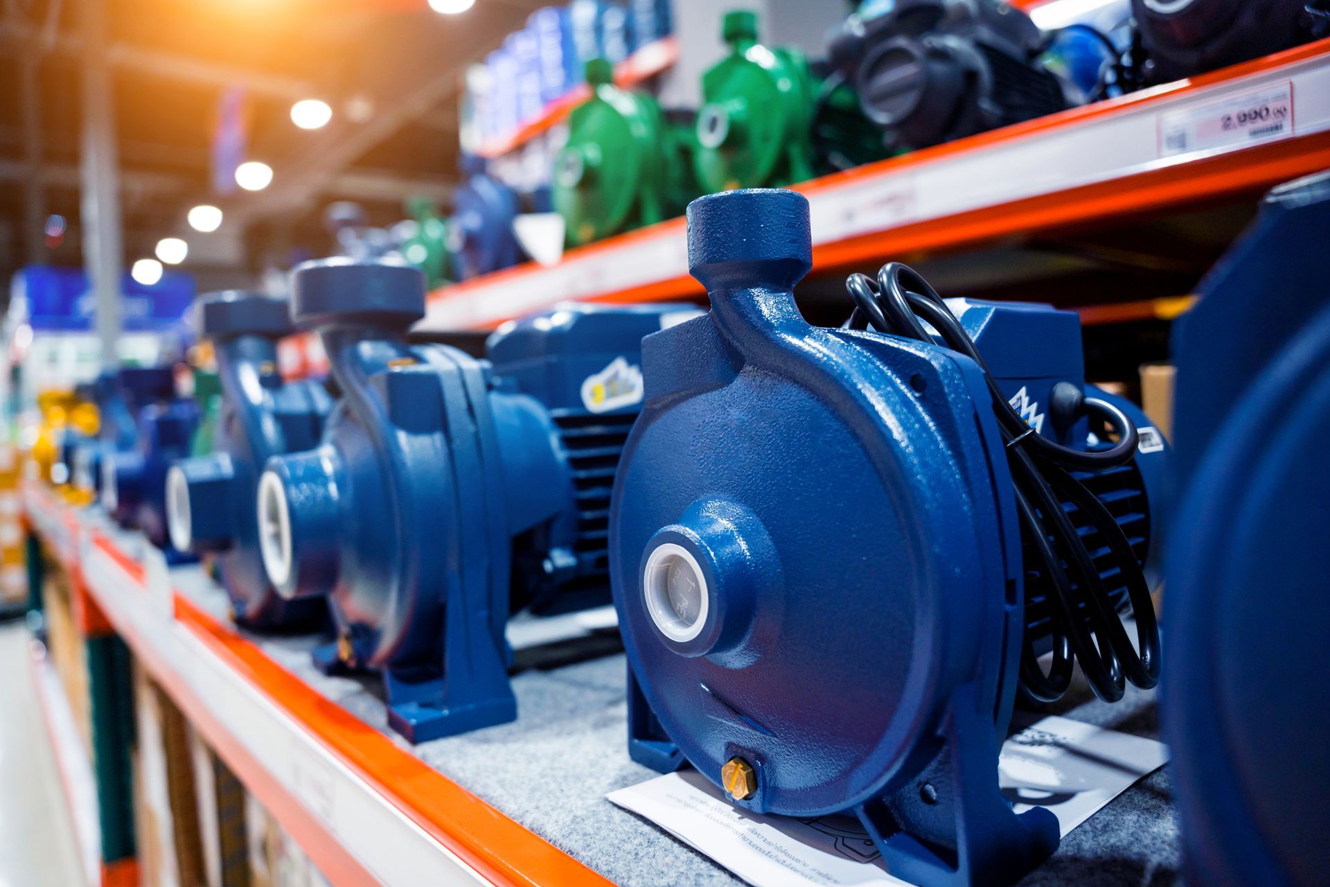 Row of blue water pumps on a store shelf, white flange, black electrical cables.