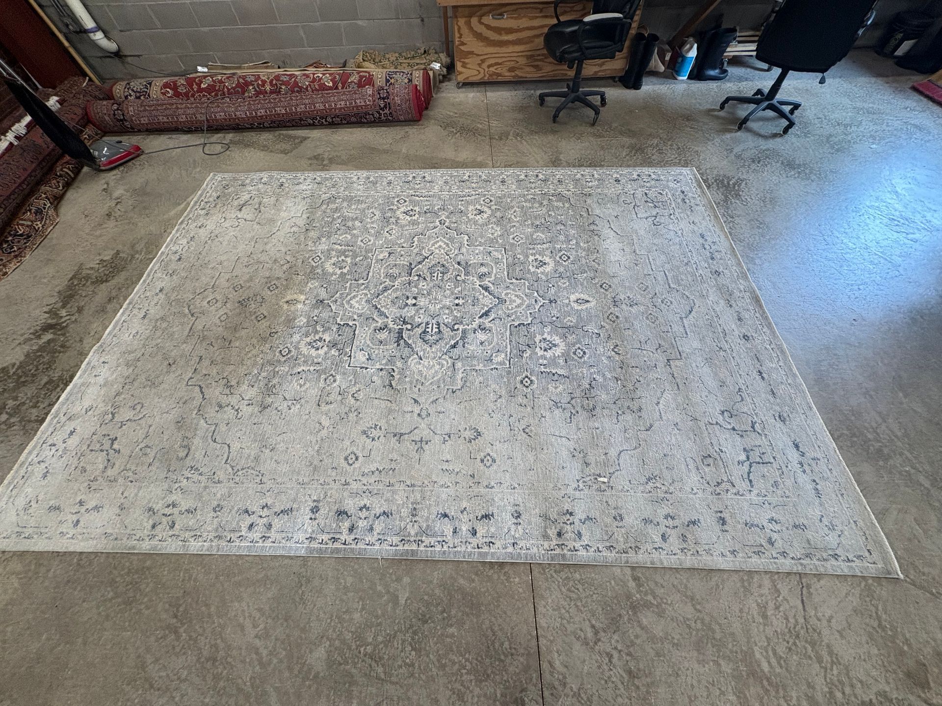 Light cream patterned area rug centered on a concrete floor in an industrial-style room.