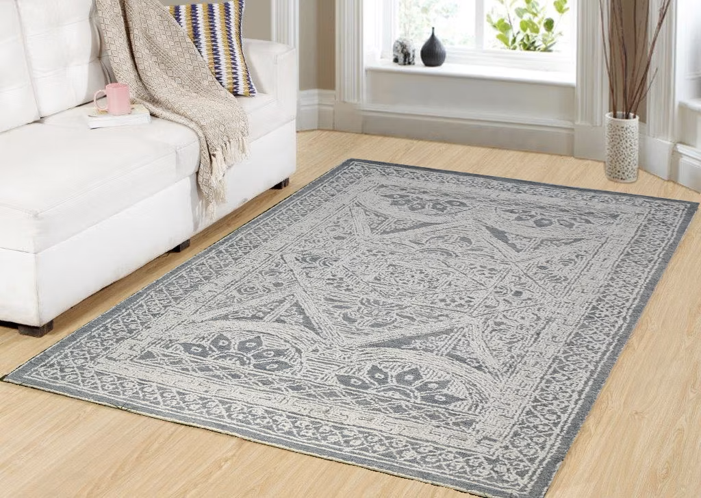 Gray patterned area rug on a light wood floor beside a white sofa in a bright living room