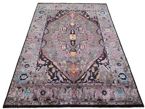 Antique patterned rug with a pink, gray, and black central medallion on a light background