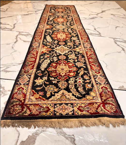Long runner rug with black, red, and cream floral pattern on a light marble floor