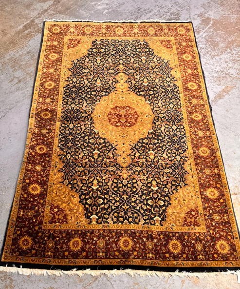 Ornate Persian-style rug with dark floral center, gold border, and central medallion on a beige floor.