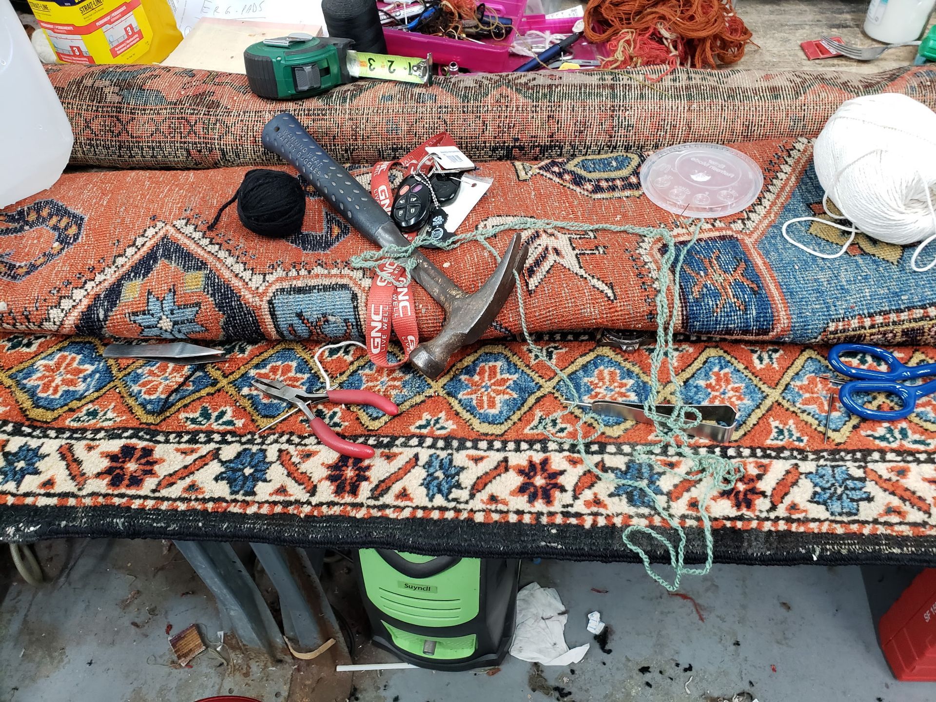 Patterned carpeted workbench with tools and supplies, including a hammer, tape measure, cup, and power tool.