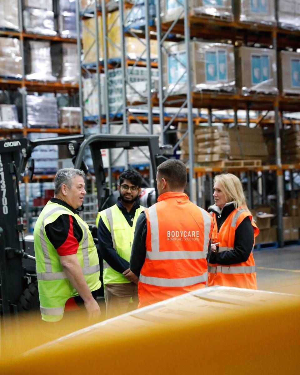 A group of people are standing in a warehouse talking to each other.