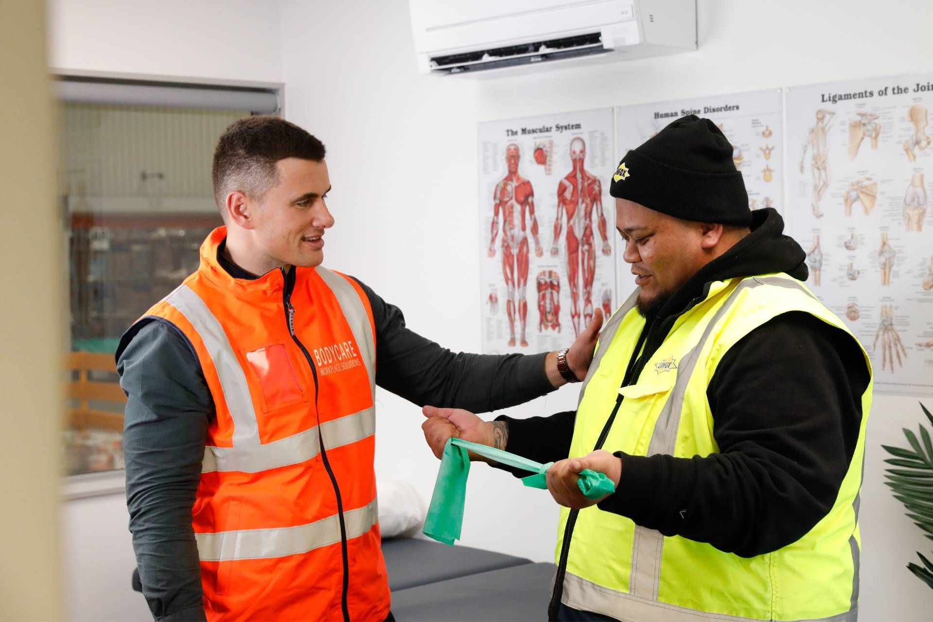 Two men in safety vests are talking to each other in a room.