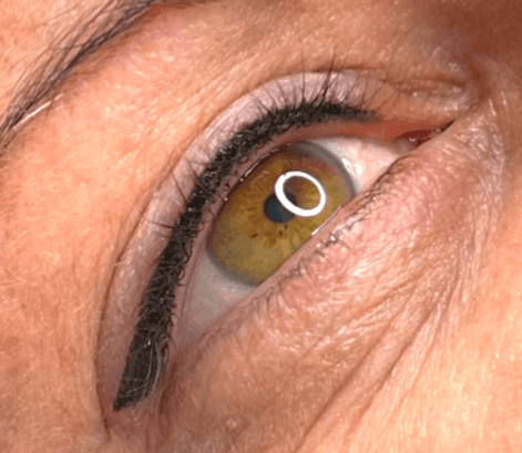 Nahaufnahme eines Auges mit semi-permanentem, dunklem, tätowiertem Lidstrich auf dem oberen Wimpernkranz.