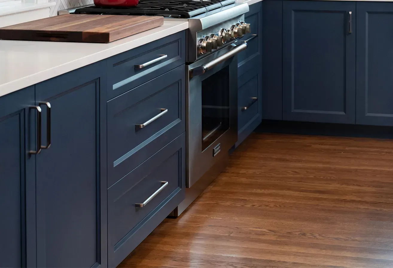 Modern kitchen with navy cabinets, stainless steel oven, wooden countertops, and hardwood floor