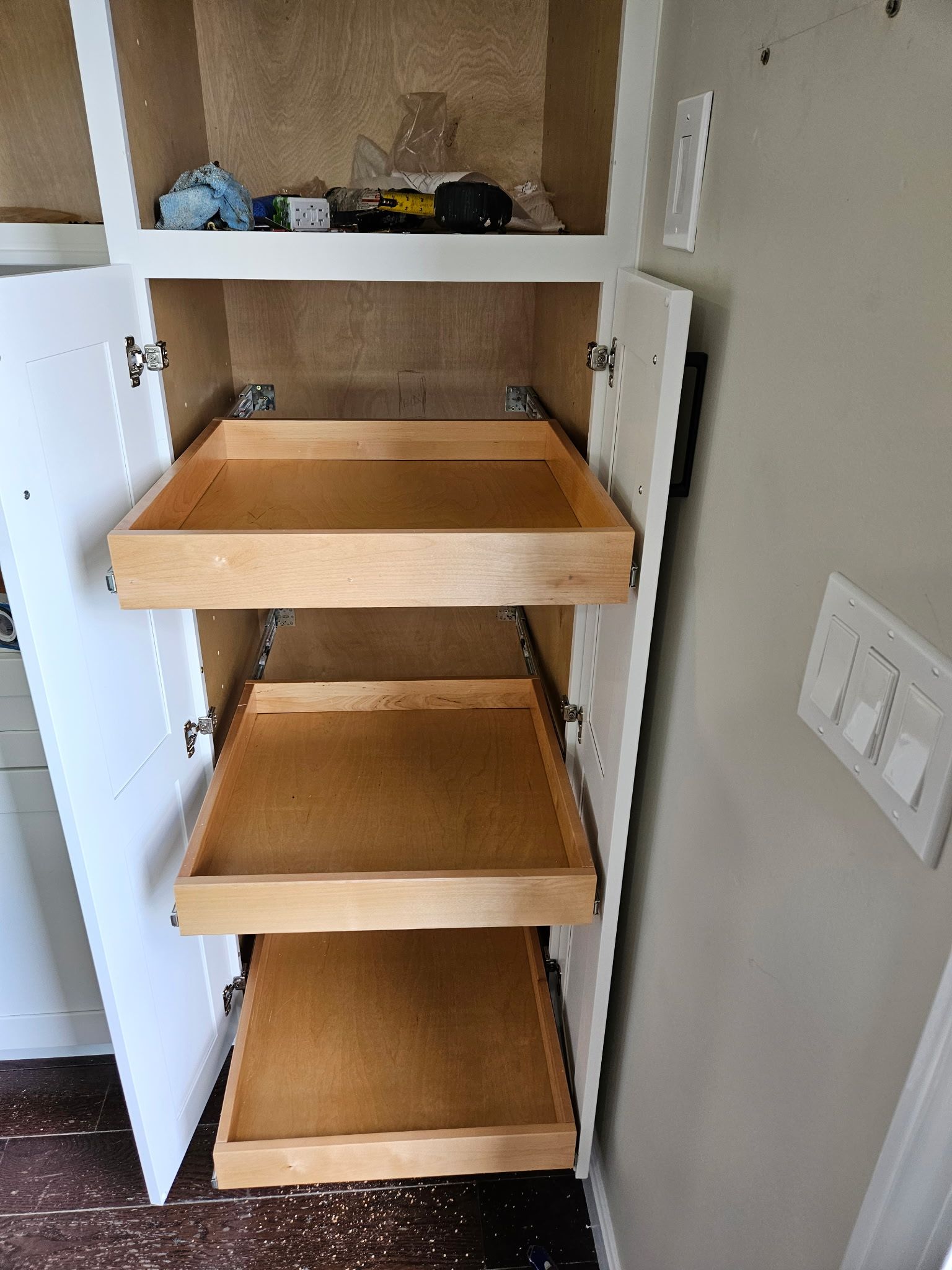 Open cabinet with pull-out wooden shelves in a kitchen or pantry.