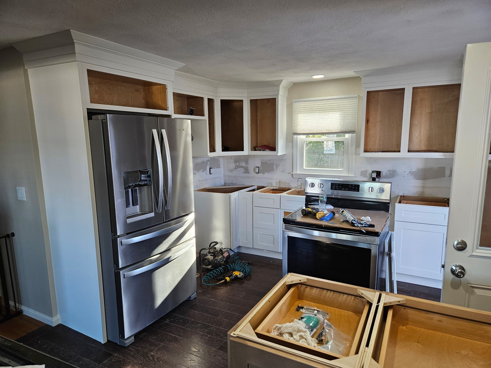 Small kitchen with stainless steel appliances, white cabinets, and a window above the sink.