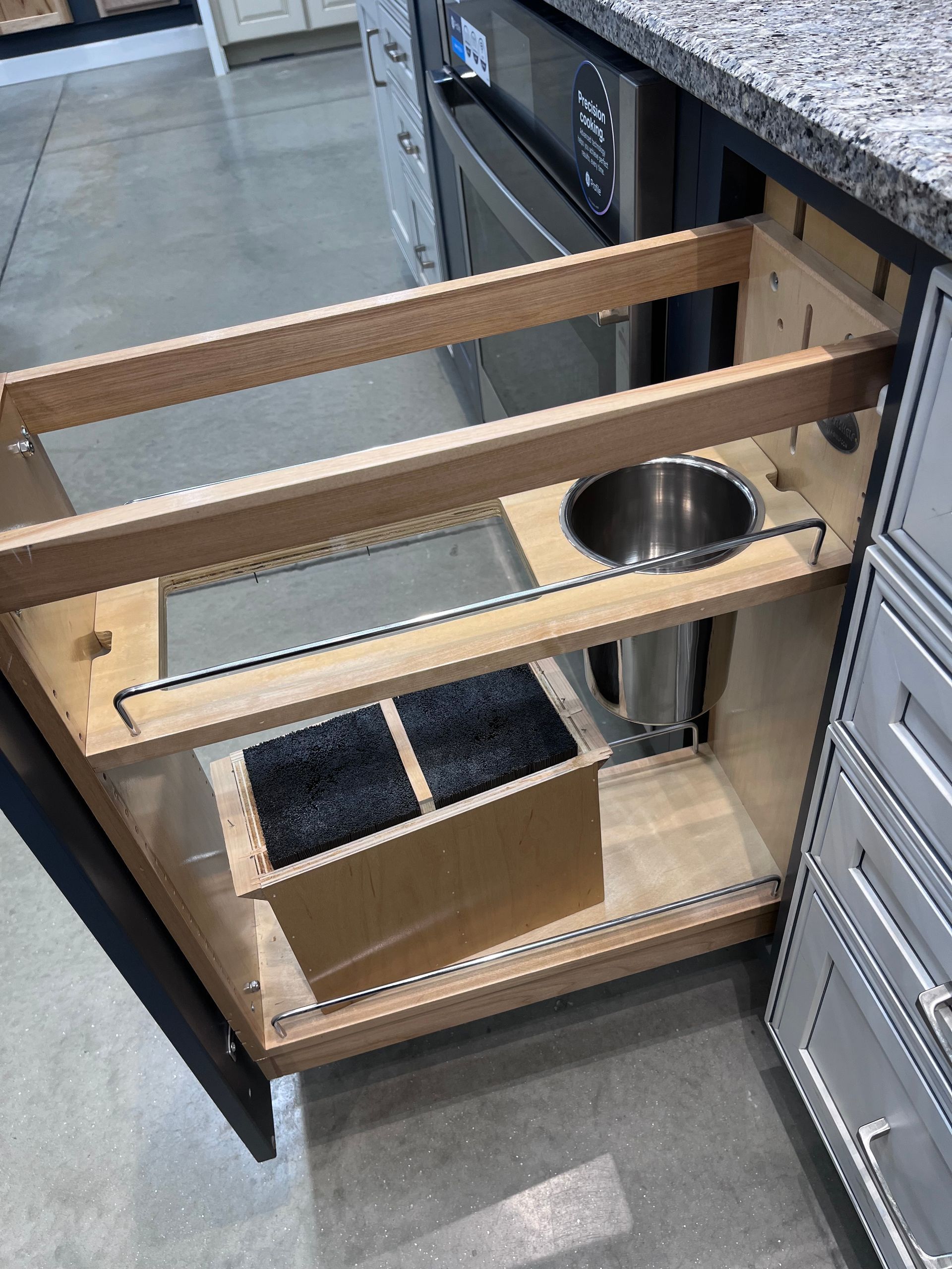 Pull-out wooden drawer with pet bowl and storage bins in a kitchen cabinet