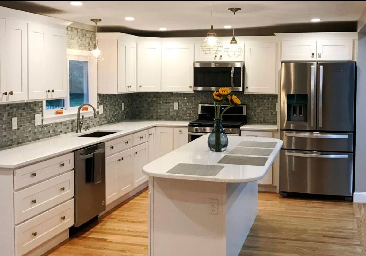 Modern white kitchen with island, stainless steel appliances, and gray tile backsplash