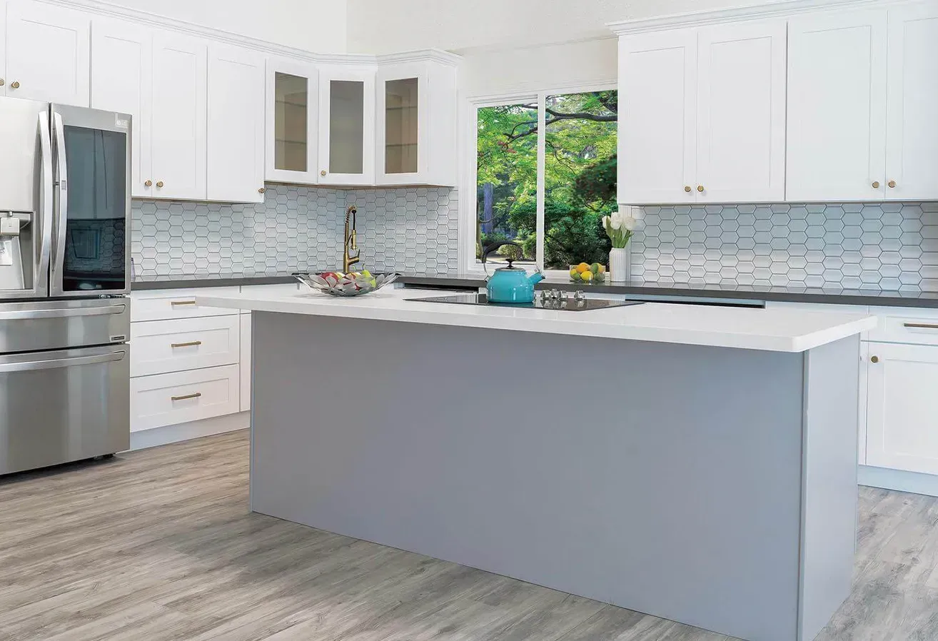 Bright modern kitchen with white cabinets, gray island, stainless steel appliances, and blue-gray backsplash.