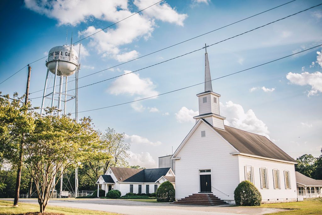 A white church with a water tower in the background.