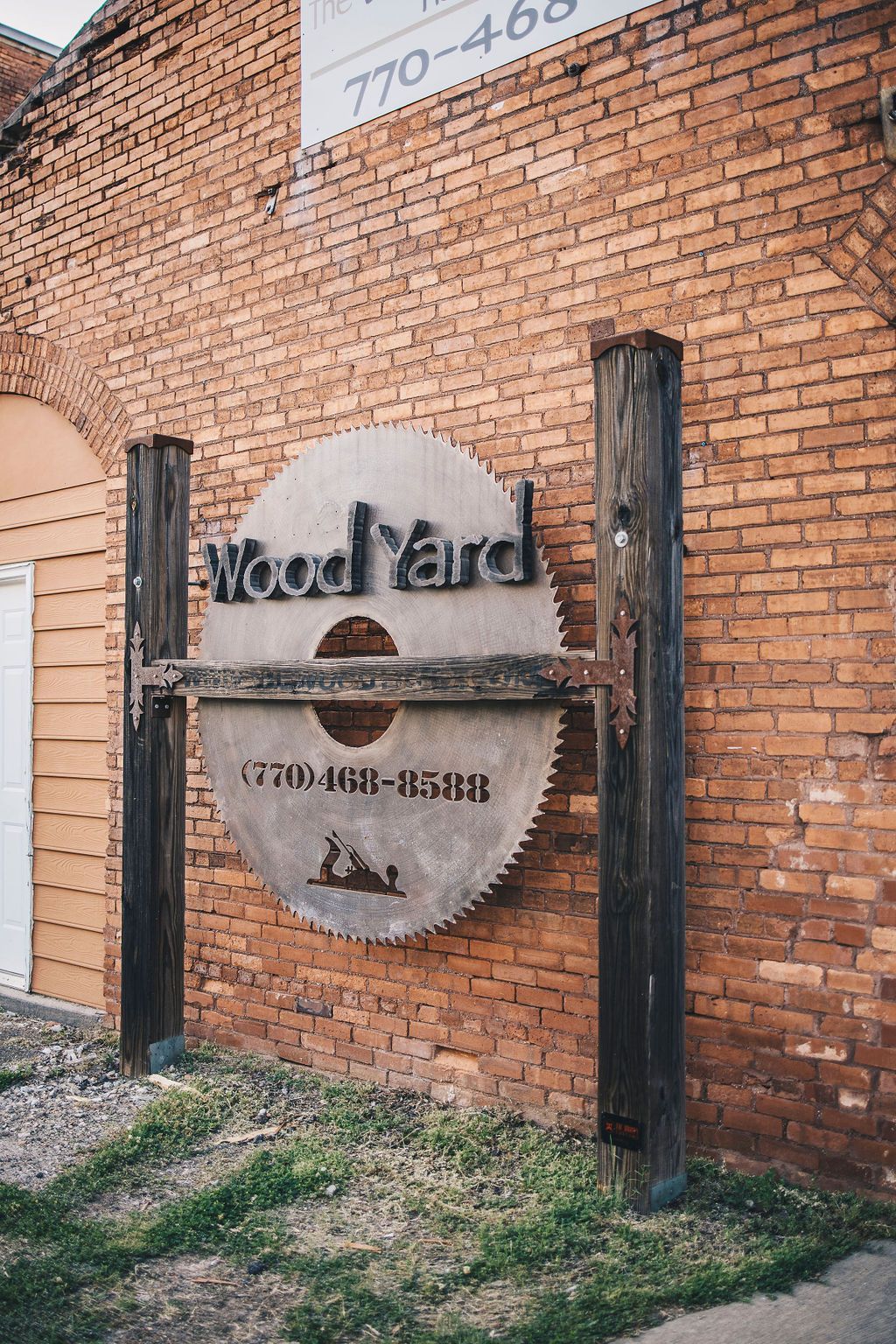 A sign that looks like a saw blade is on a brick wall.