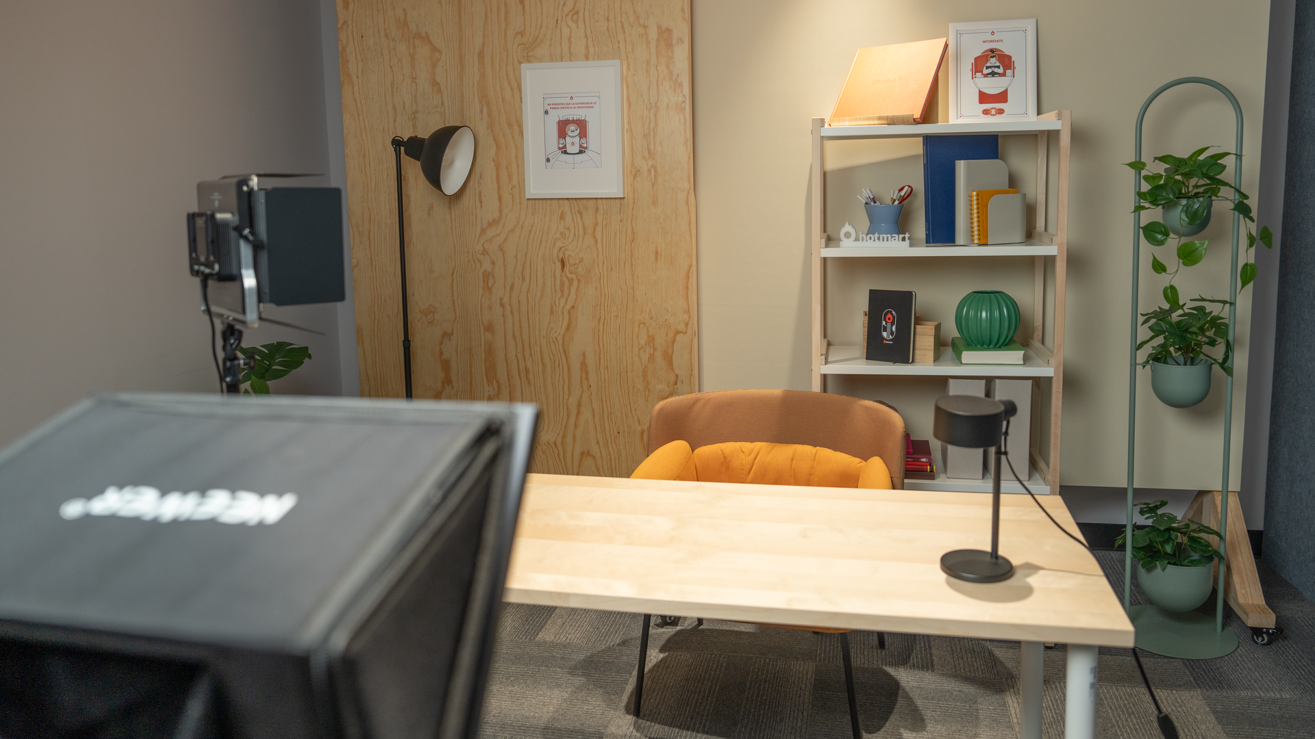 Uma sala com uma mesa, cadeira, estante, luminária e projetor.