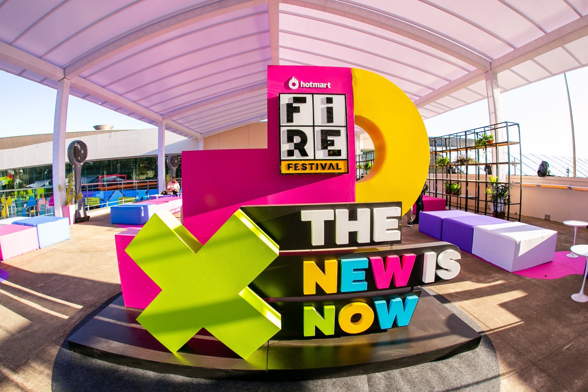 A colorful sign that says the new is now is in front of a building.