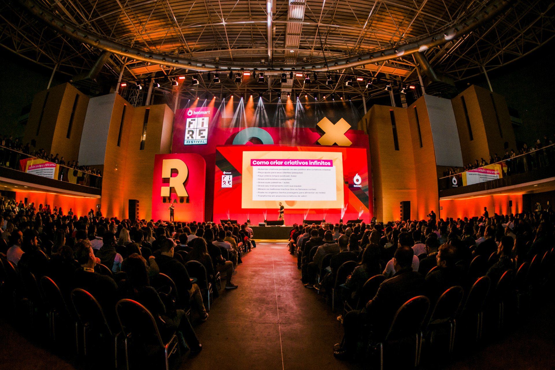 A large crowd of people are sitting in a large auditorium watching a presentation.