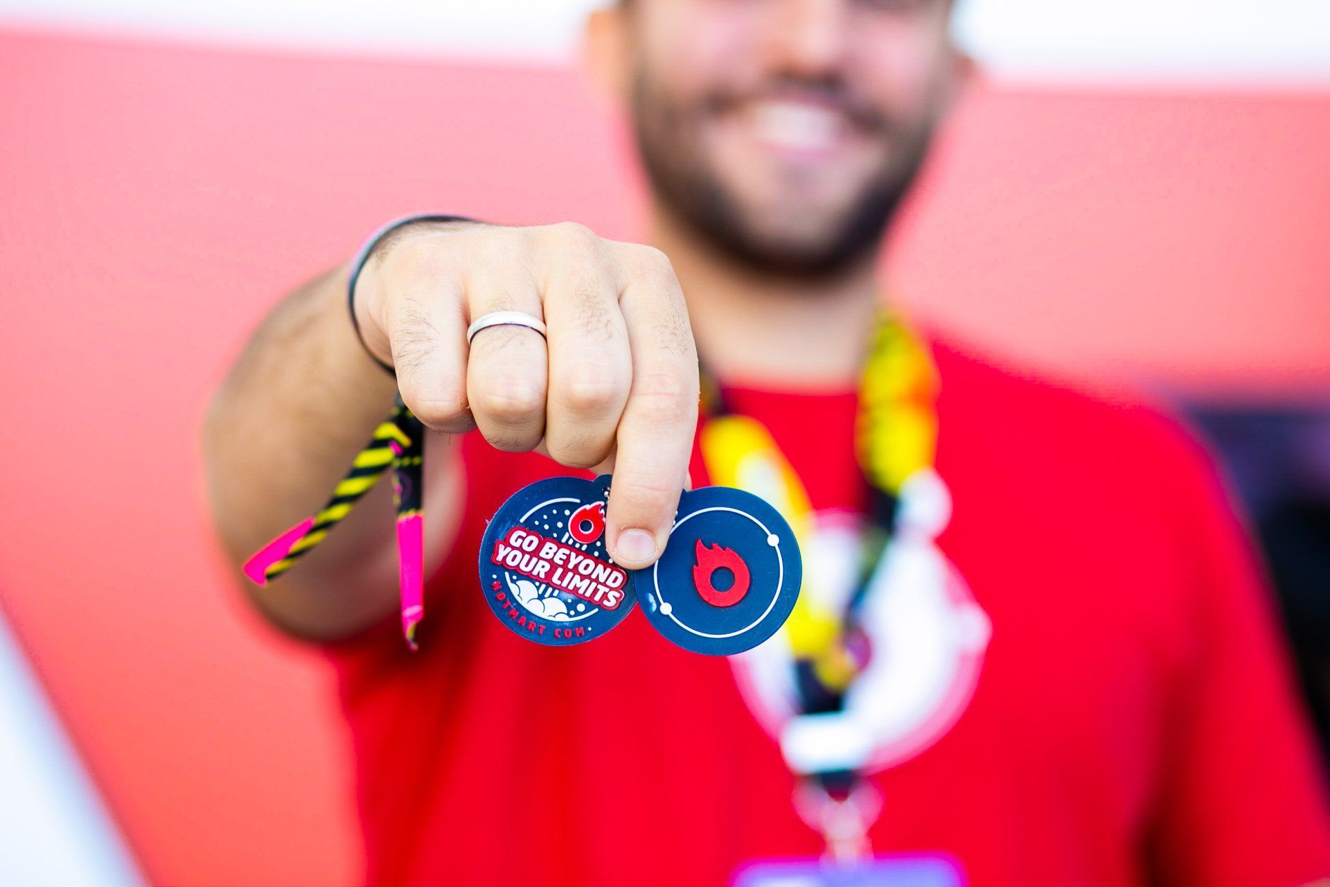 A man in a red shirt is holding two badges in his hand.