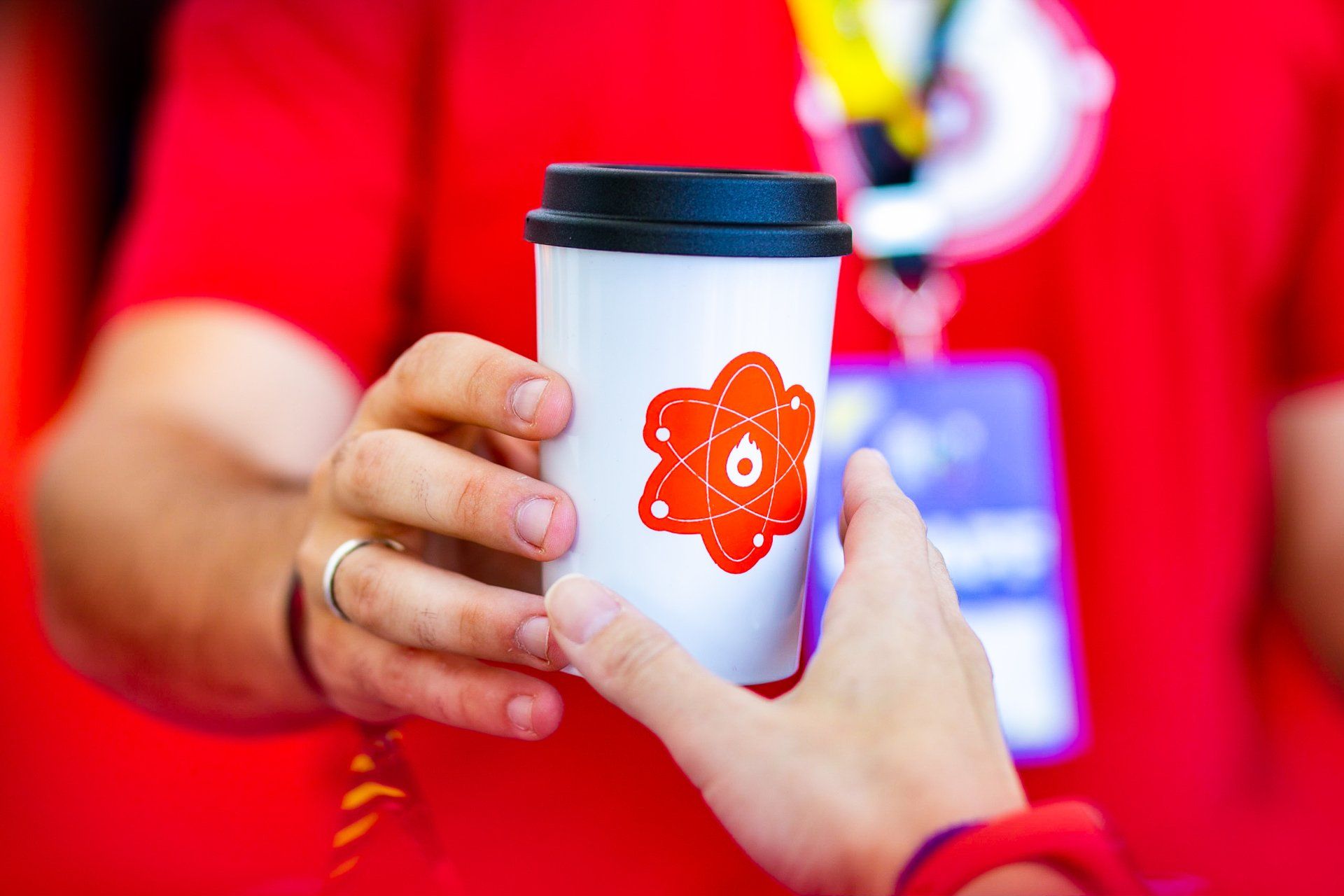 A person is holding a cup of coffee with an atom on it.