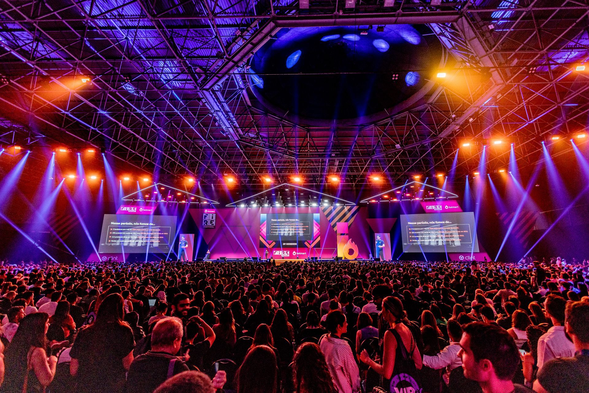 A large crowd of people are sitting in front of a stage at a concert.