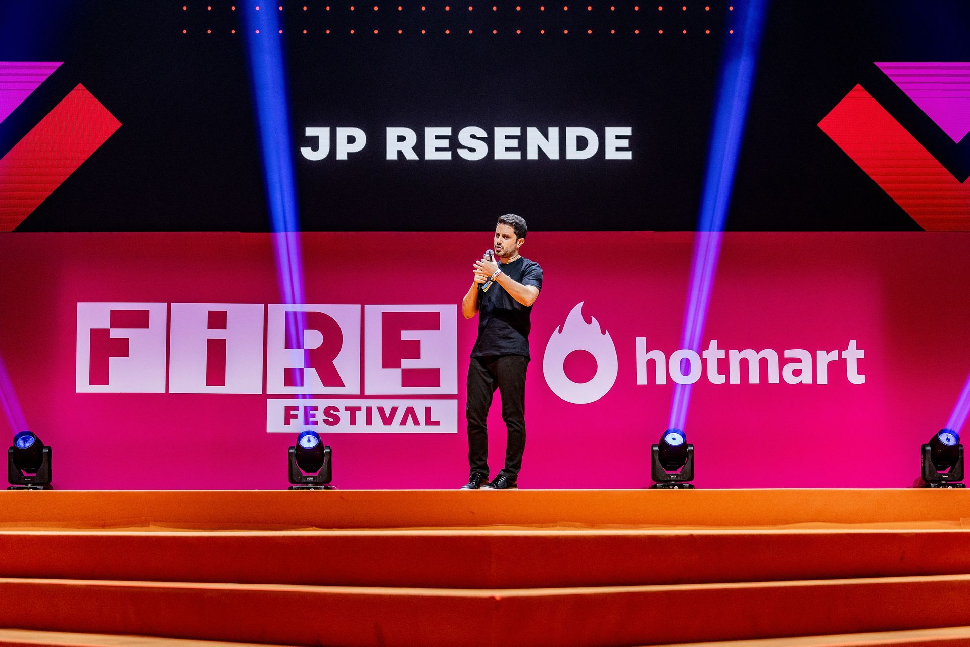 A man is standing on a stage in front of a sign that says fire festival