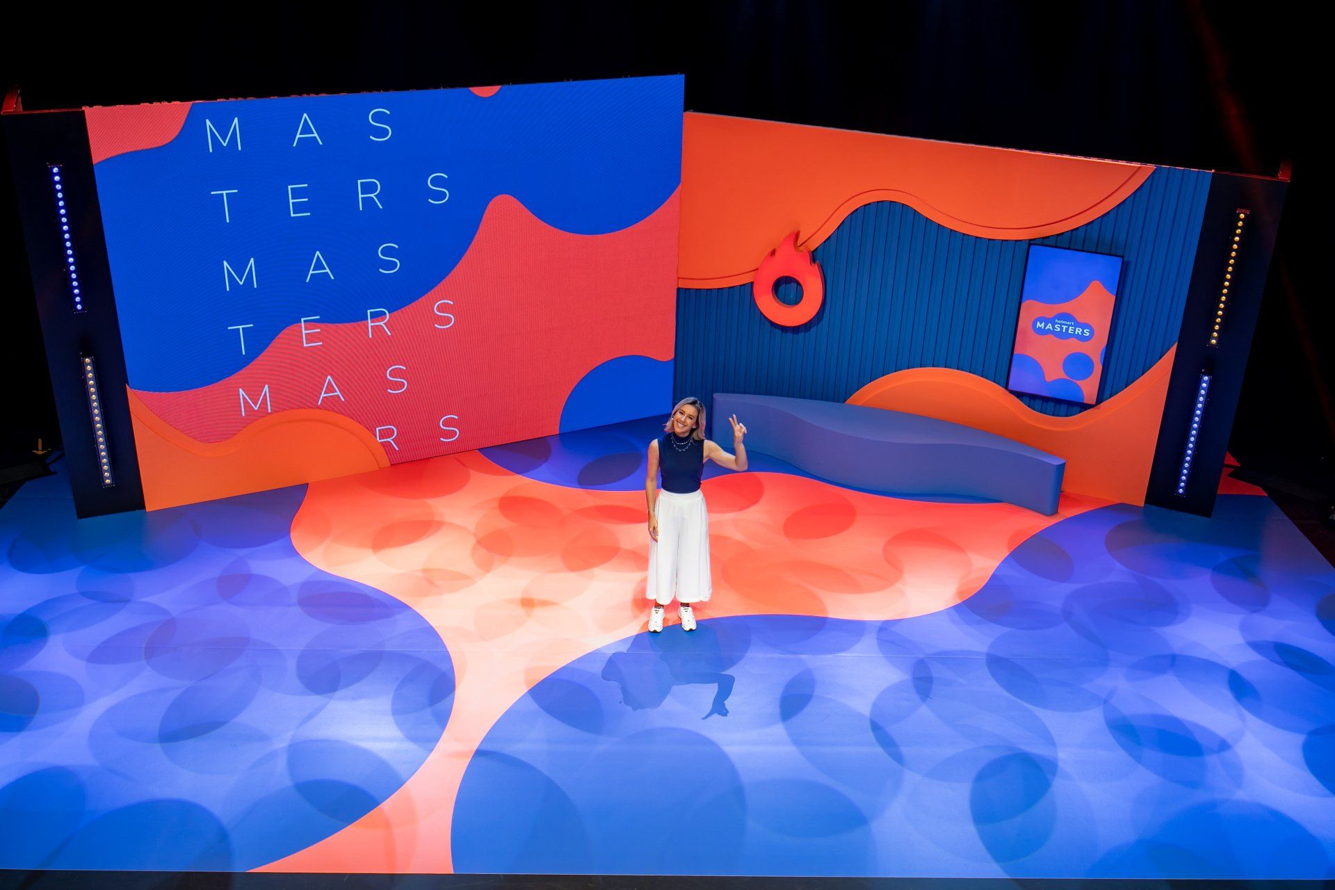 A woman is standing on a stage in front of a large screen.