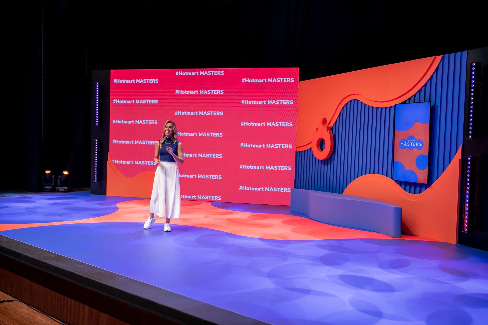 A woman is standing on a stage in front of a large screen.