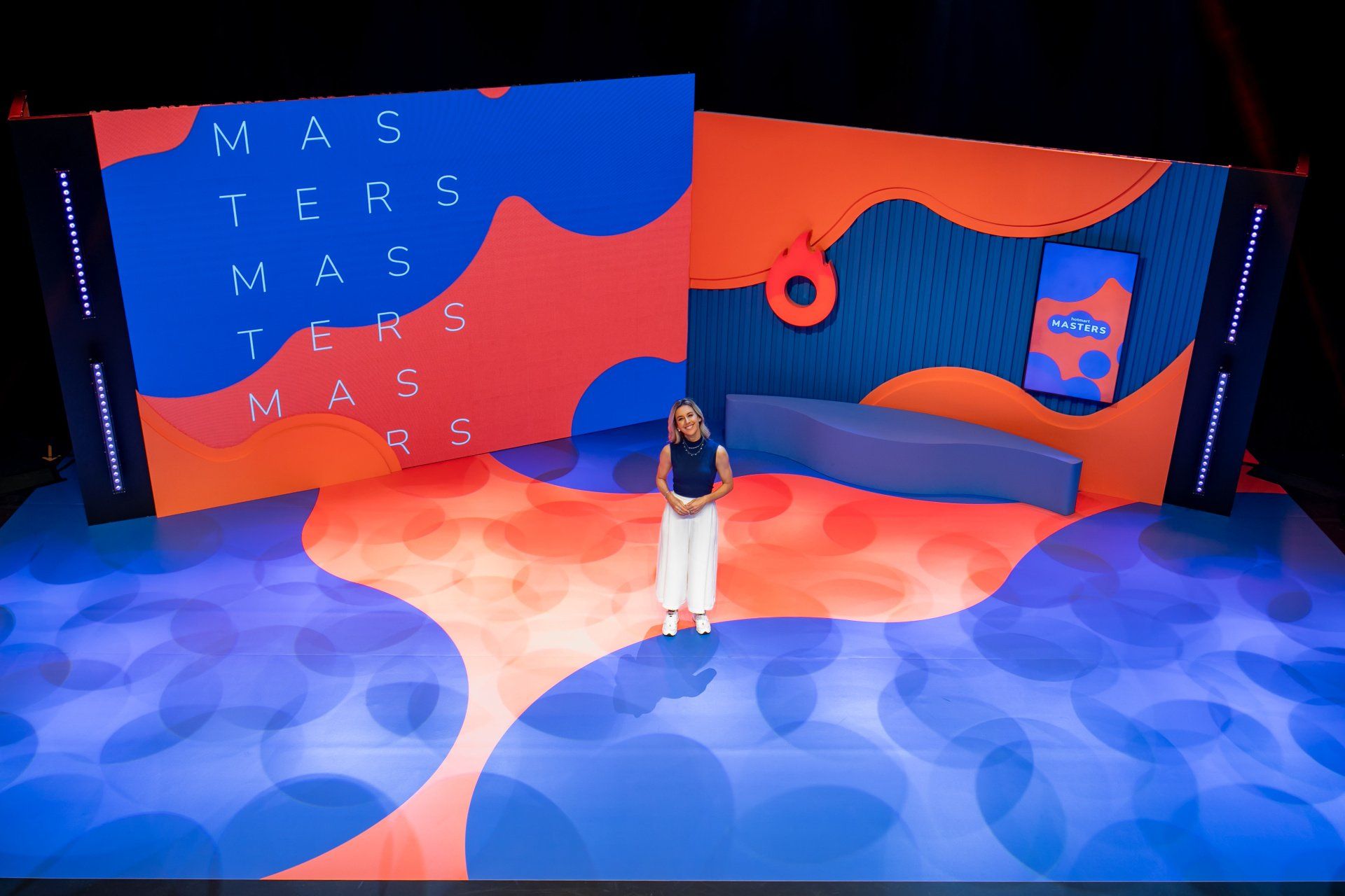 A woman is standing on a stage in front of a large screen.